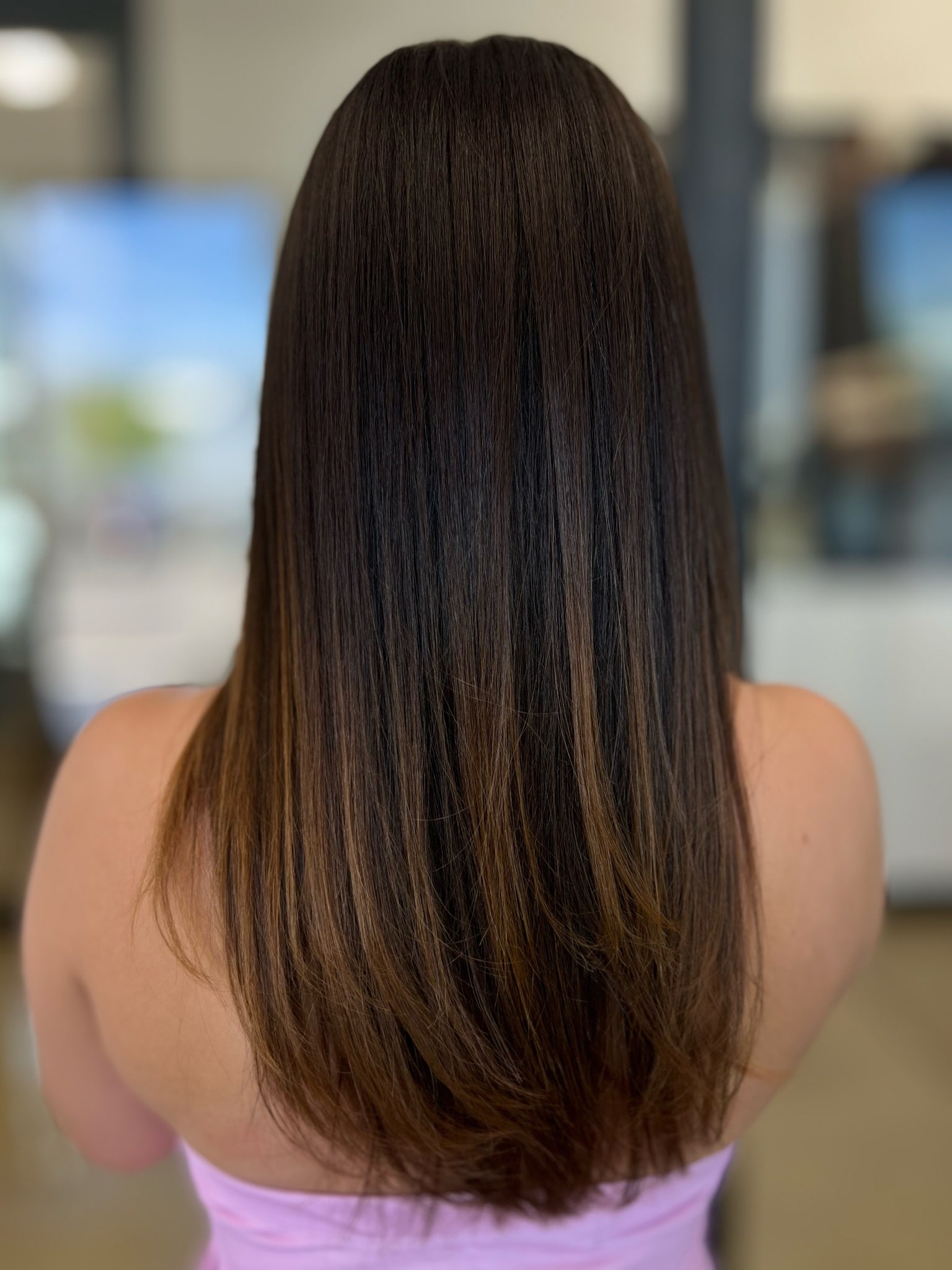Long, smooth dark brown hair with caramel ends viewed from behind